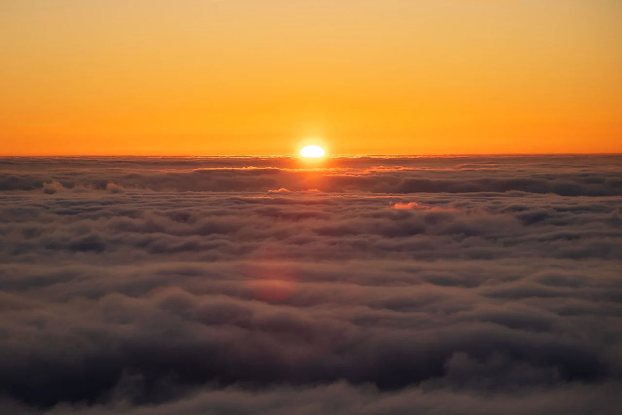 The sun rising above a sea of clouds