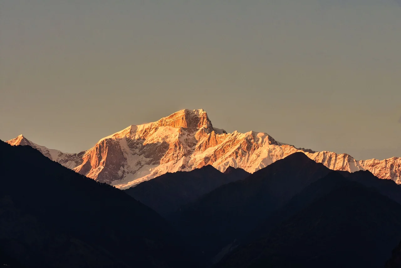 A mountain peak glowing gold above dark ridges